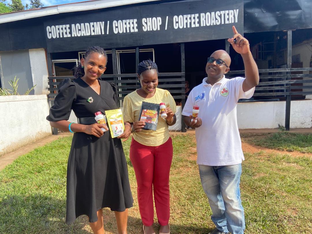 Three people presenting Kibajjo ginger products outside a coffee academy